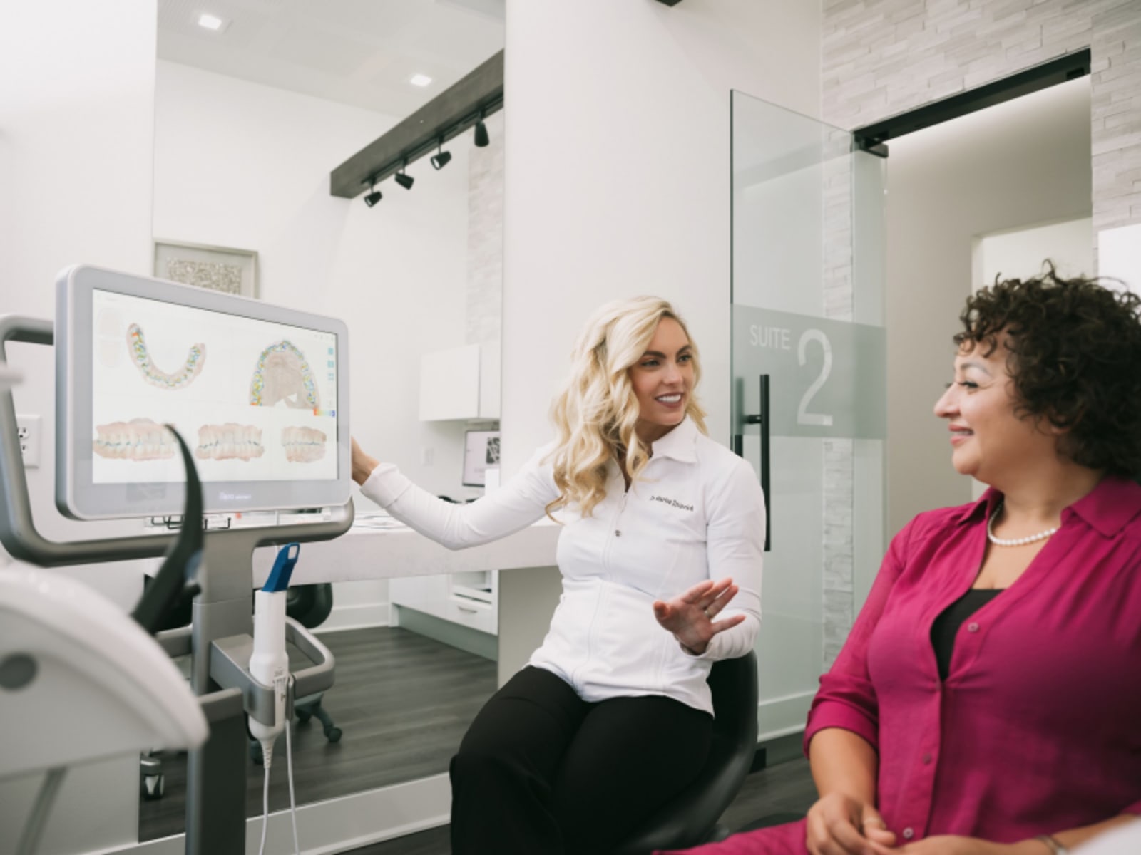Dentist pointing to digital x-ray display showing dental imaging and patient records