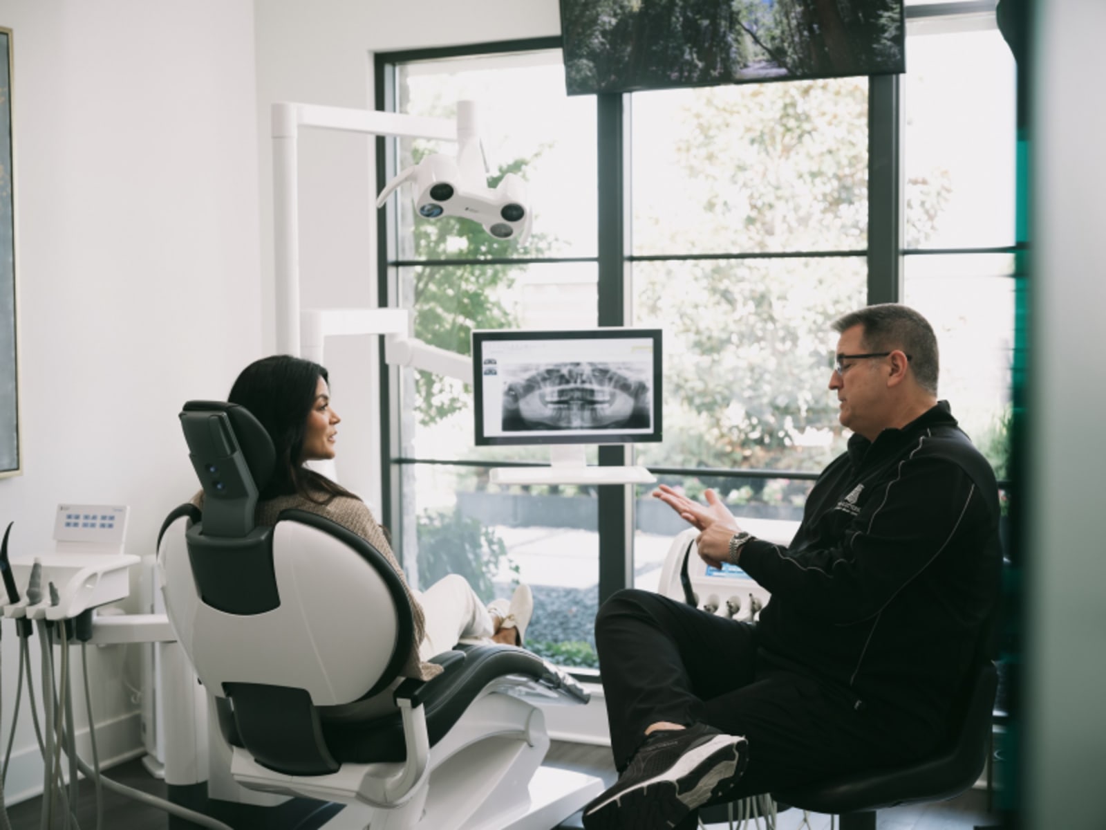 Dentist and patient having a consultation in modern dental office with natural light