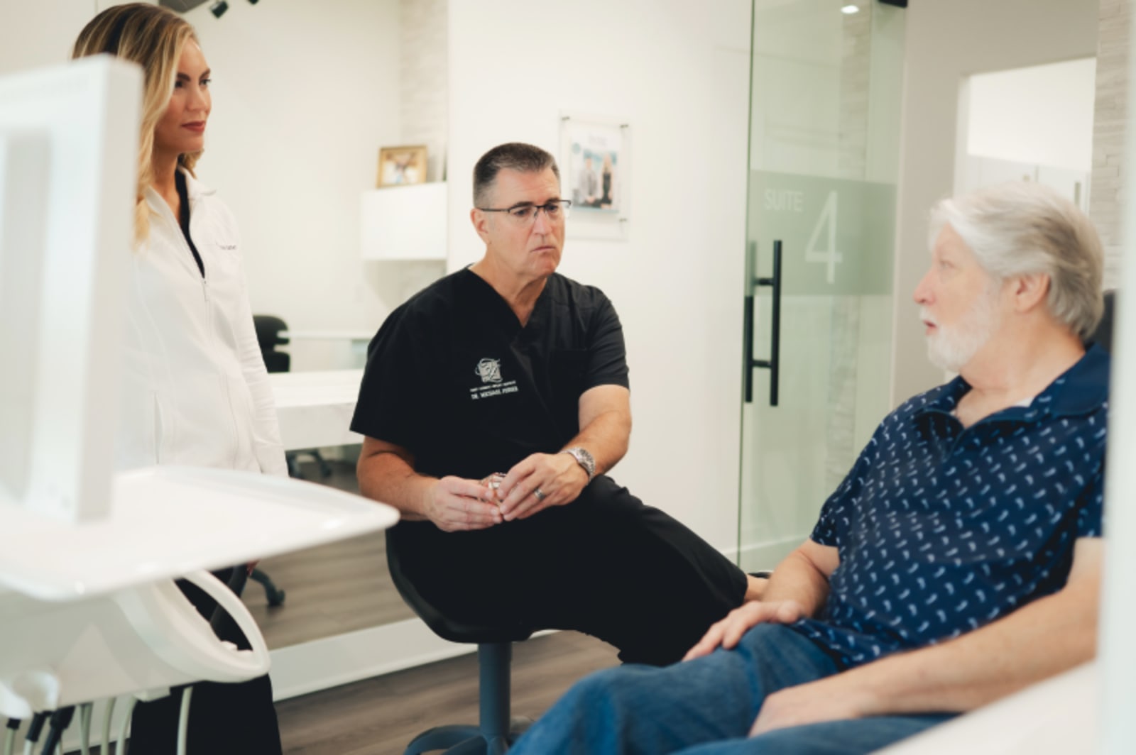 Dentist discussing implant options with female patient in dental office treatment room.