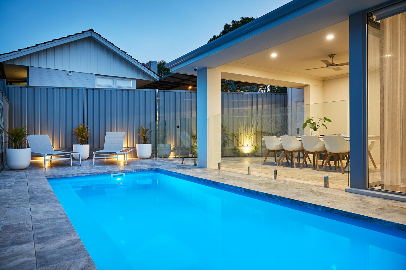 Imperial fibreglass pool lit at night beside an alfresco entertaining area