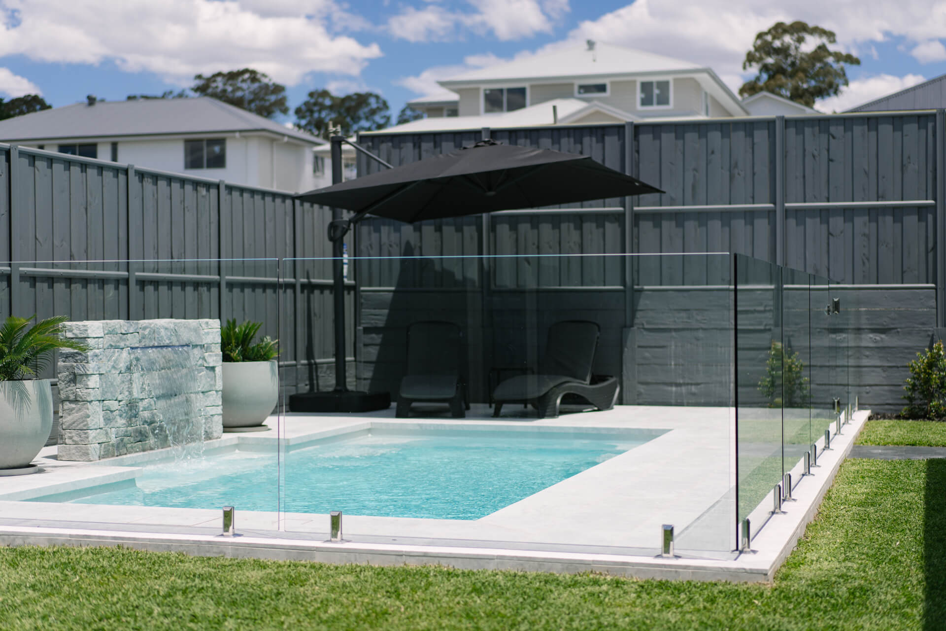 Ambassador fibreglass pool in Alabaster with glass fencing and cantilevered umbrella