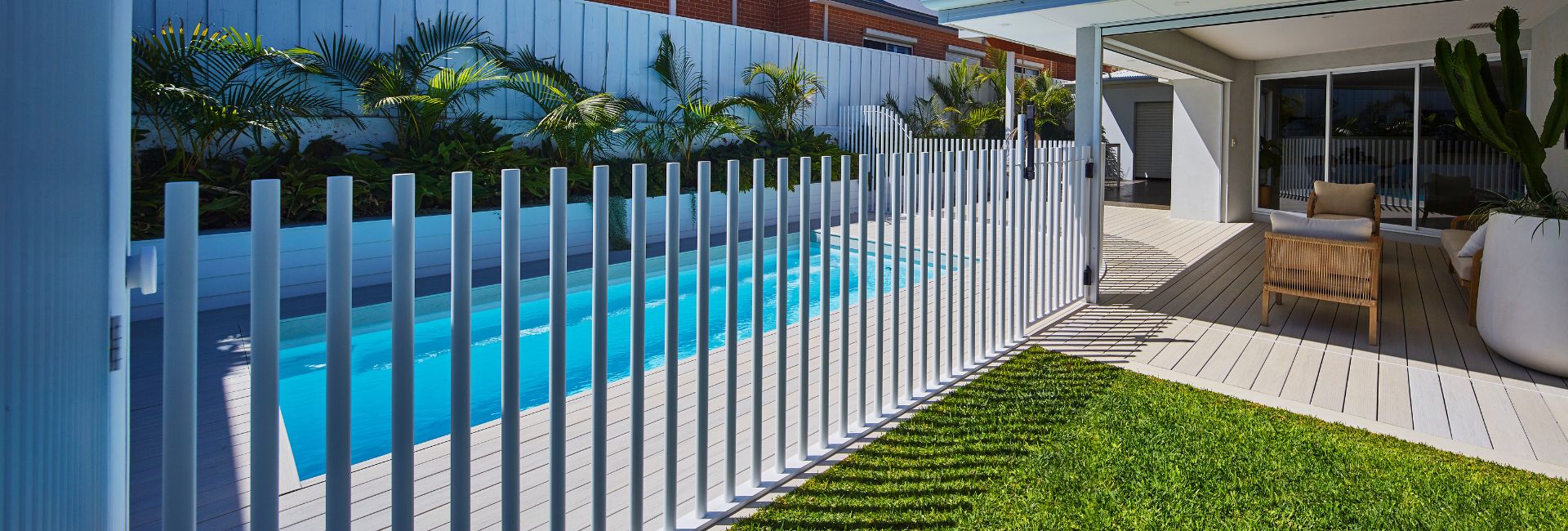 Wide view of a Hamilton Slimline 5.5m pool in Polo White behind white pool fencing