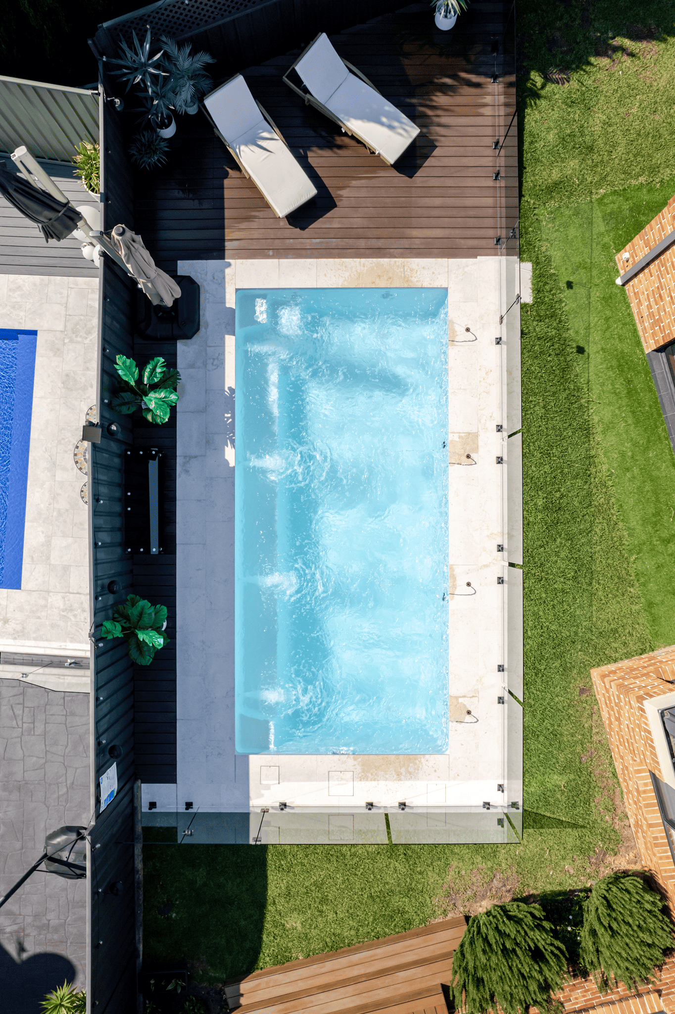 Aerial view of a fibreglass pool with sun lounges on a timber deck