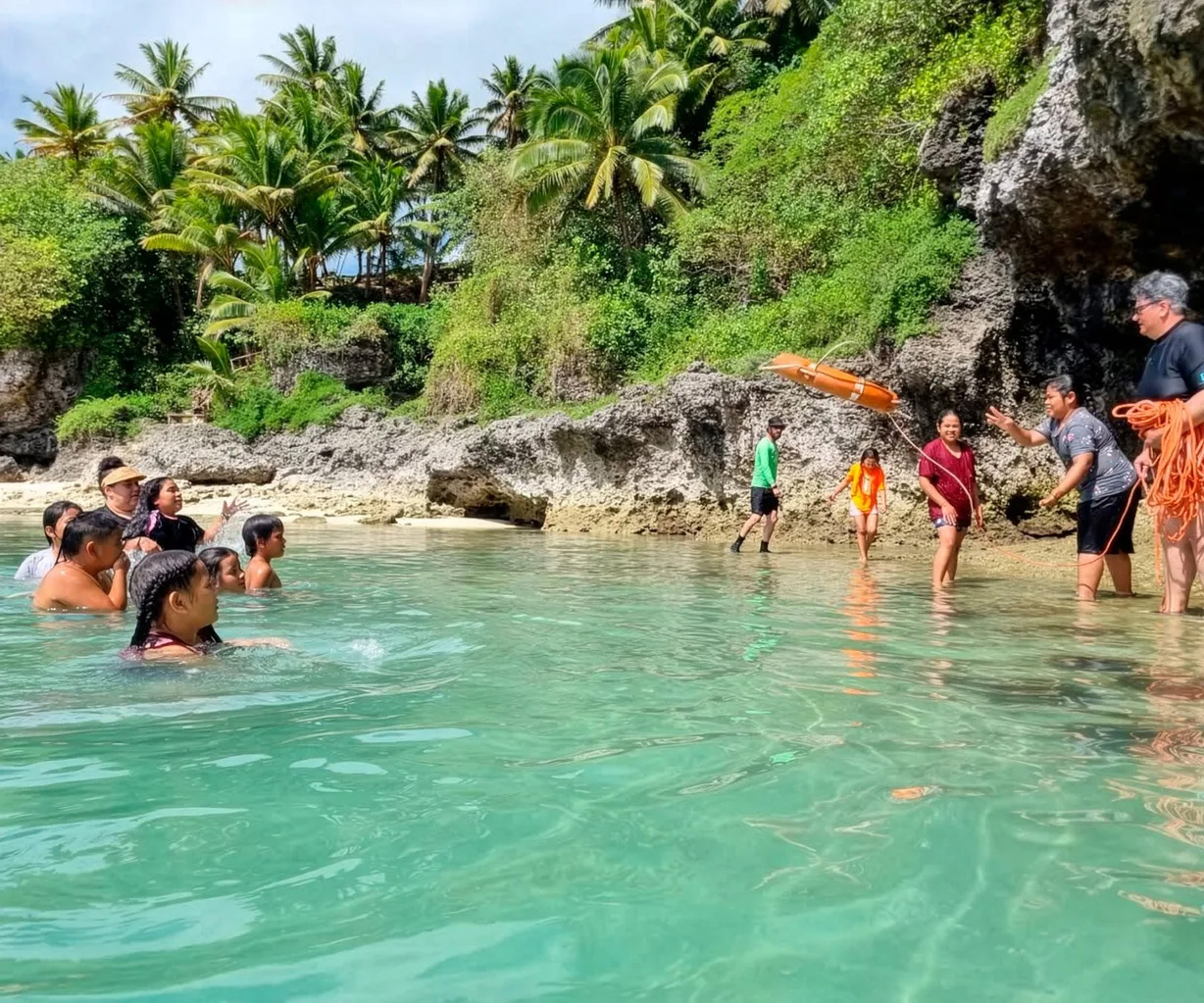 Esther in Niue showing people on the beach how to floatation aids to people in the water