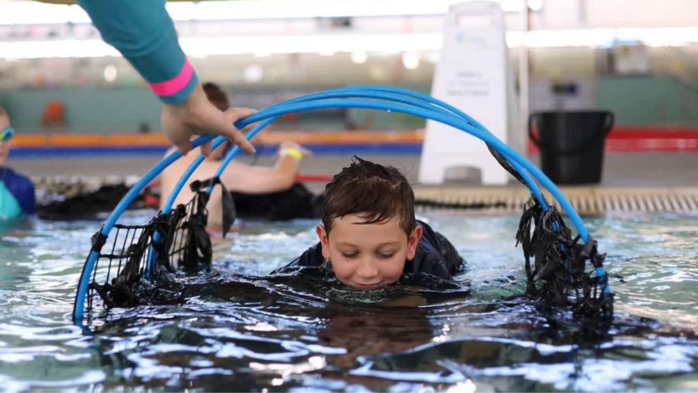 Child swimming through hoops on the water surface
