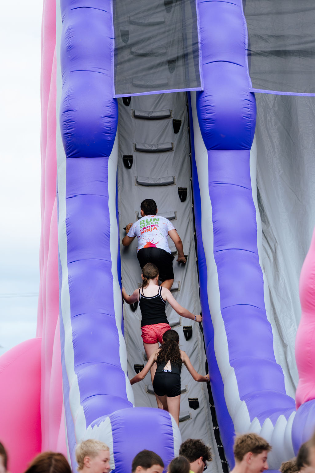 Kids climbing up a tall pink and purple inflatable at The Ninja Run Tauranga