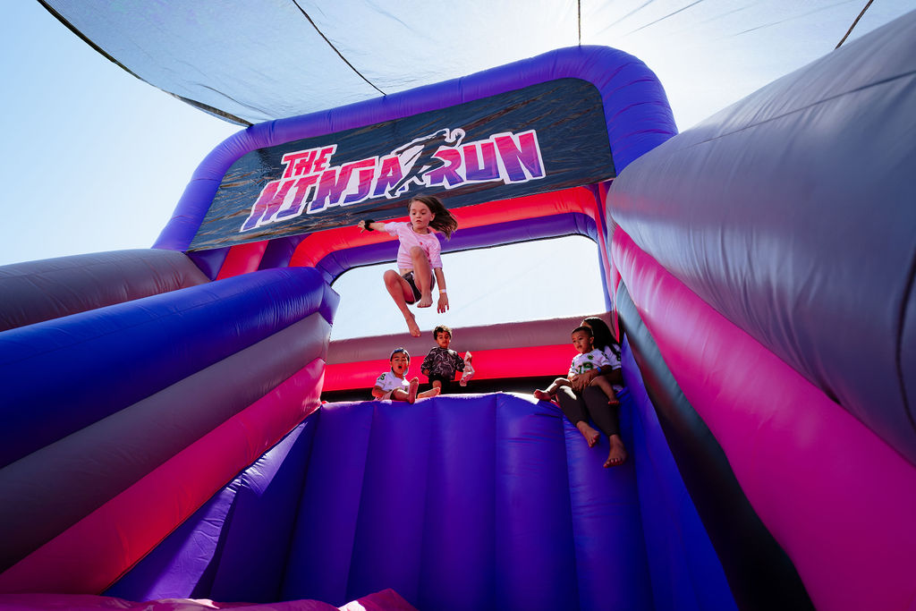 Child bouncing inside an inflatable under the Ninja Run banner