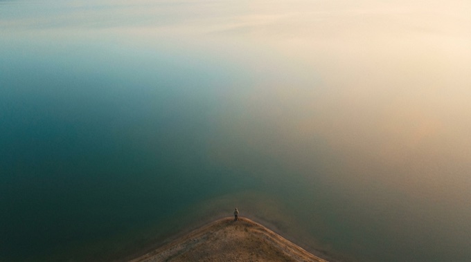 Capacity Audit Tool — aerial view of person standing at the edge of calm water