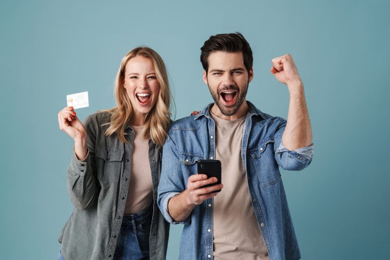 Smiling couple celebrating with a smartphone and credit card