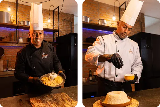 Chef sorrindo segurando prato com sobremesa cremosa ao lado de prato com outra sobremesa, mostrando preparo em ambiente de cozinha profissional com parede de tijolos.