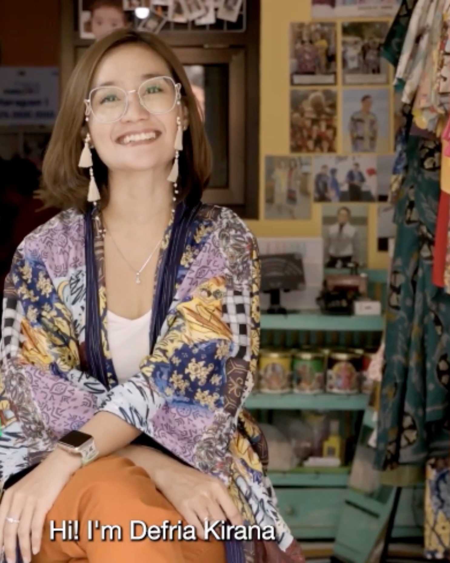 Laptop and smartphone on a mustard-colored fabric surface showing speakers presenting at a 'Conversations' event.