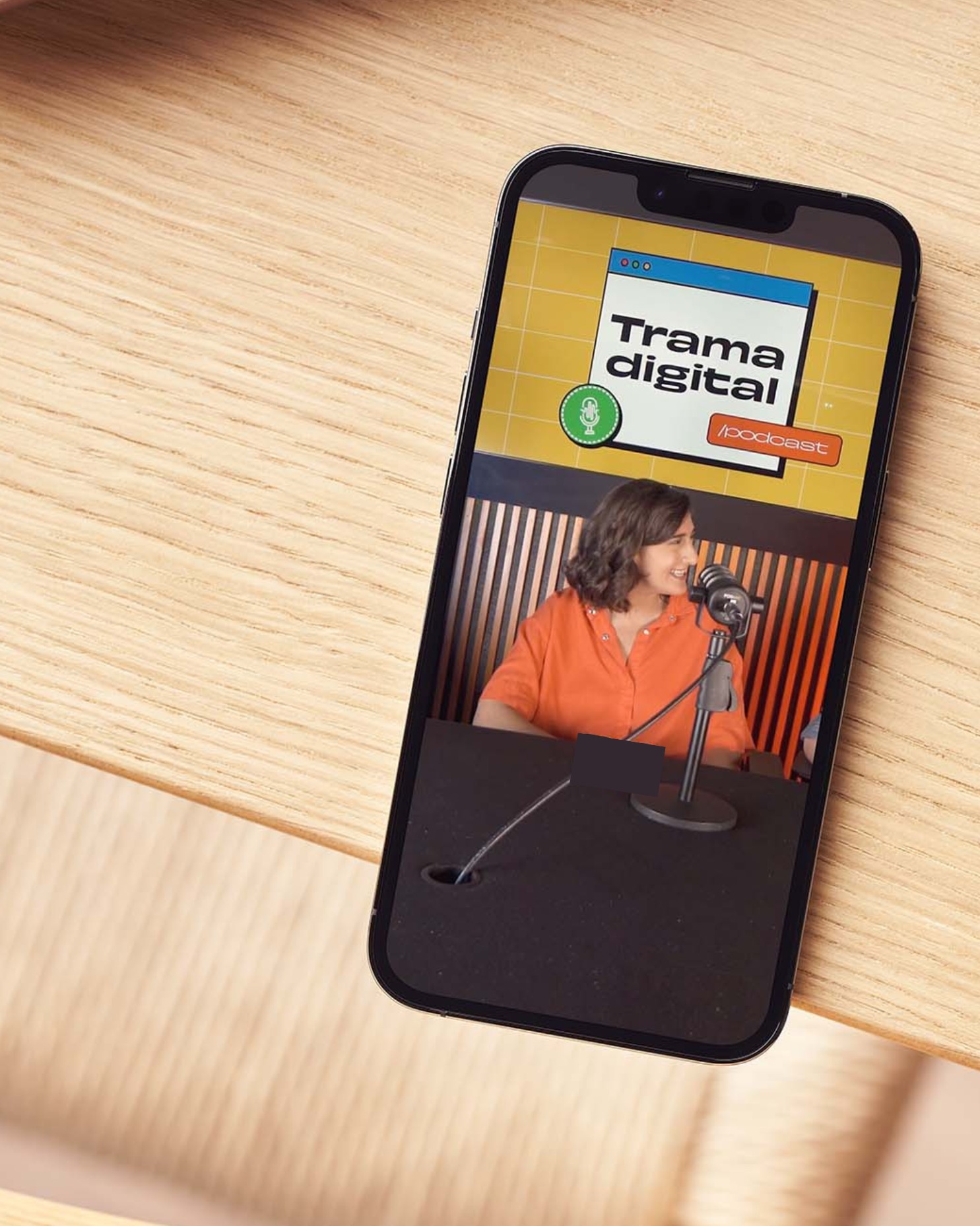 Laptop and smartphone on a mustard-colored fabric surface showing speakers presenting at a 'Conversations' event.