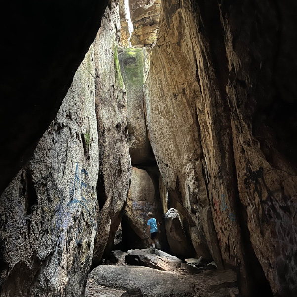 boy standing in massive rock formation 