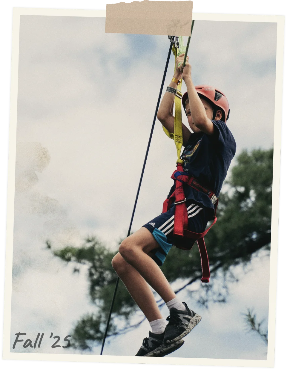 A boy is rappelling with a rope and harness