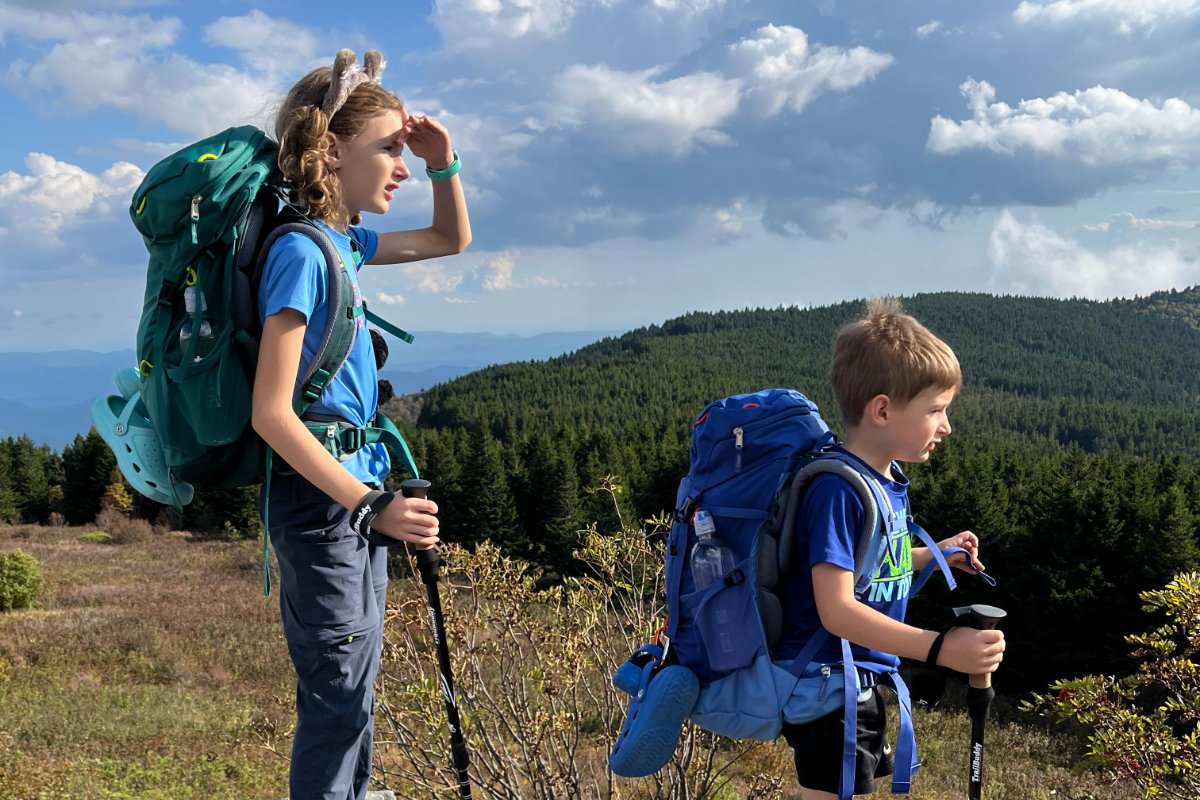 Two kids backpacking and looking out over at the mountain views