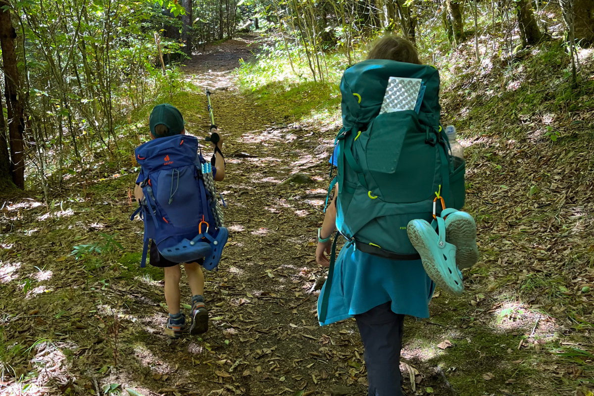 Two kids wearing backpacking gear hiking out