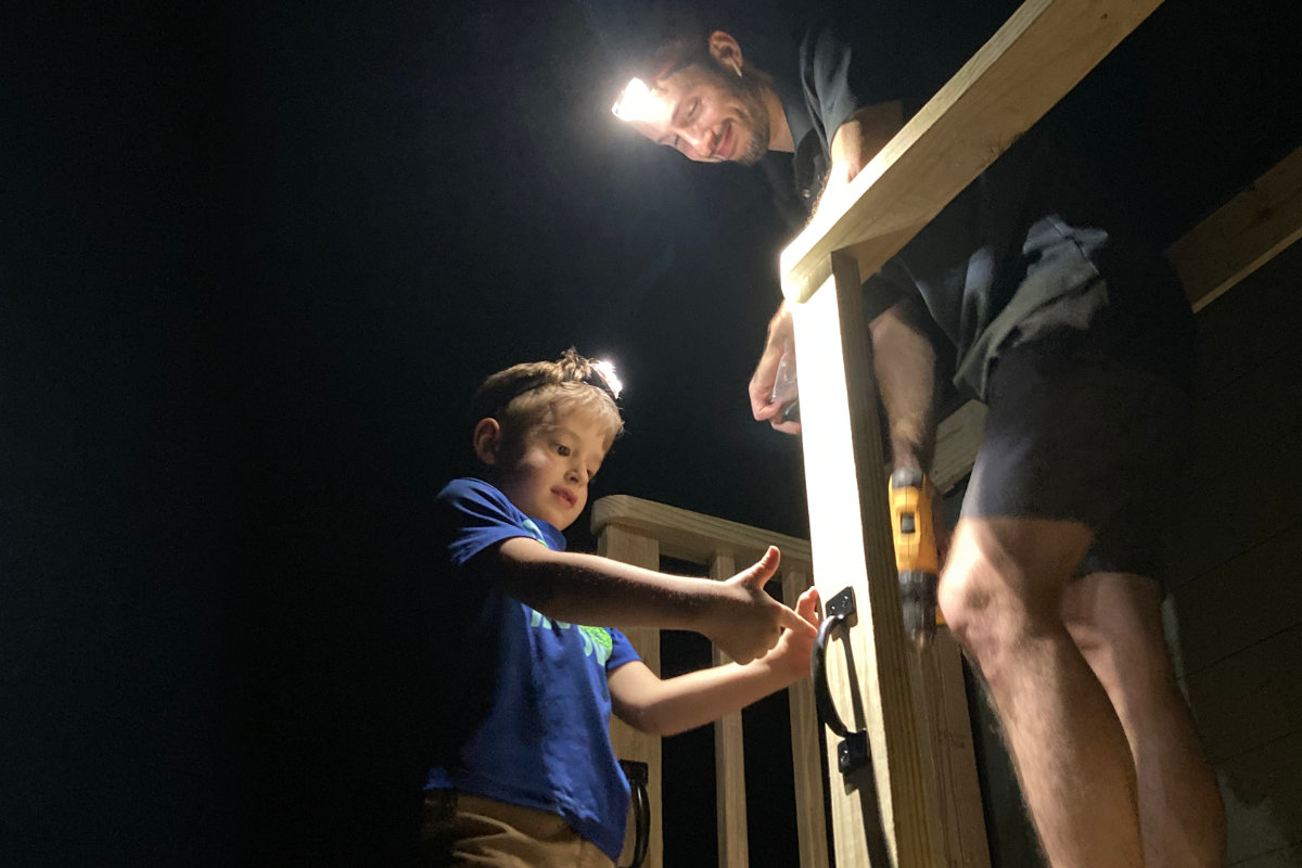 Kid and man building treehouse in the dark with headlamps