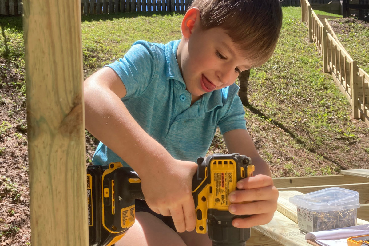 Kid drilling in screws on treehouse decking