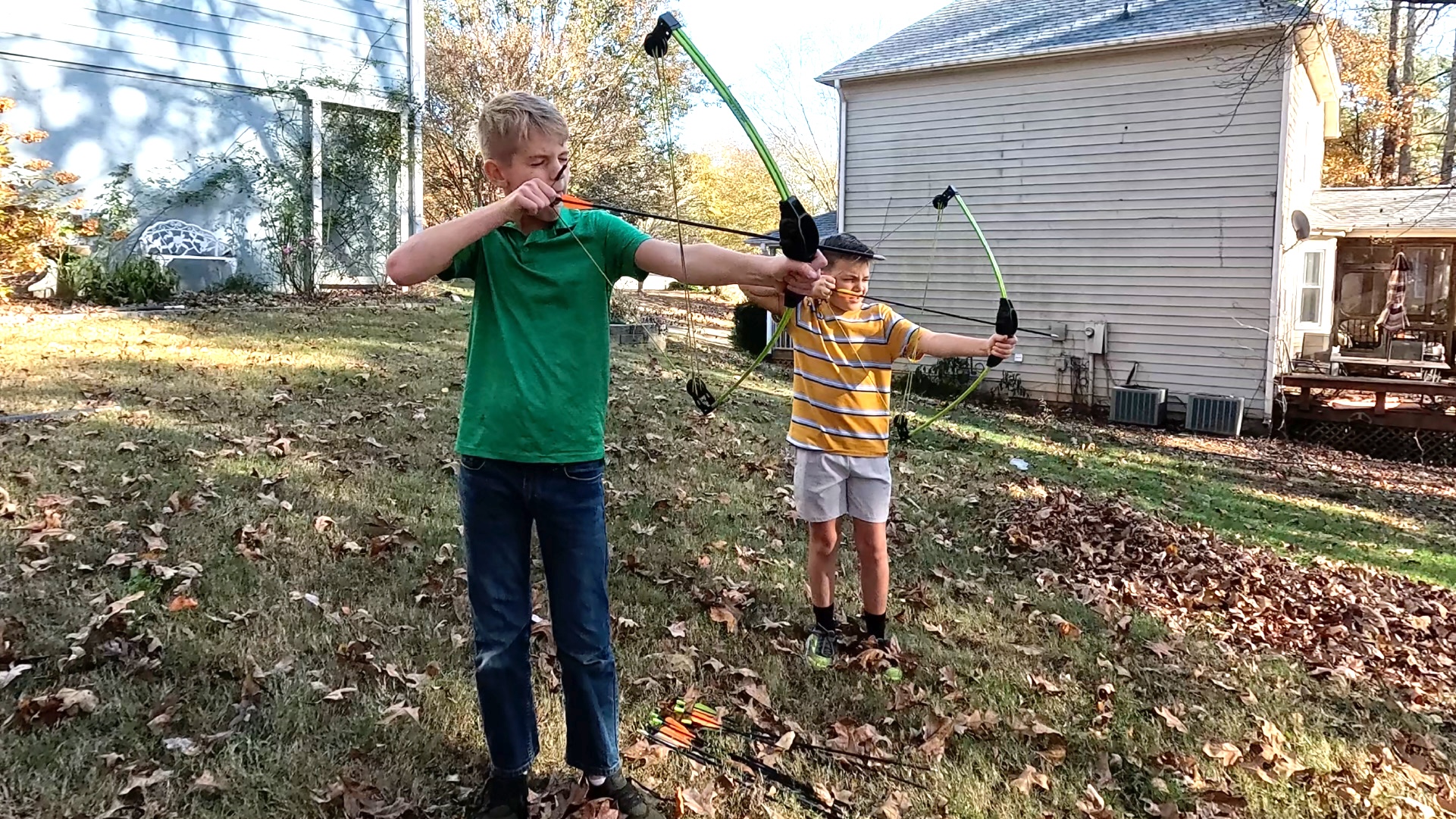 Two boys shoot bows and arrows