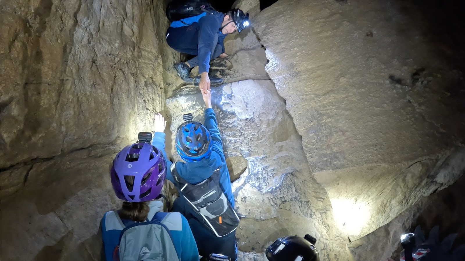 Kids climb up wall in cave