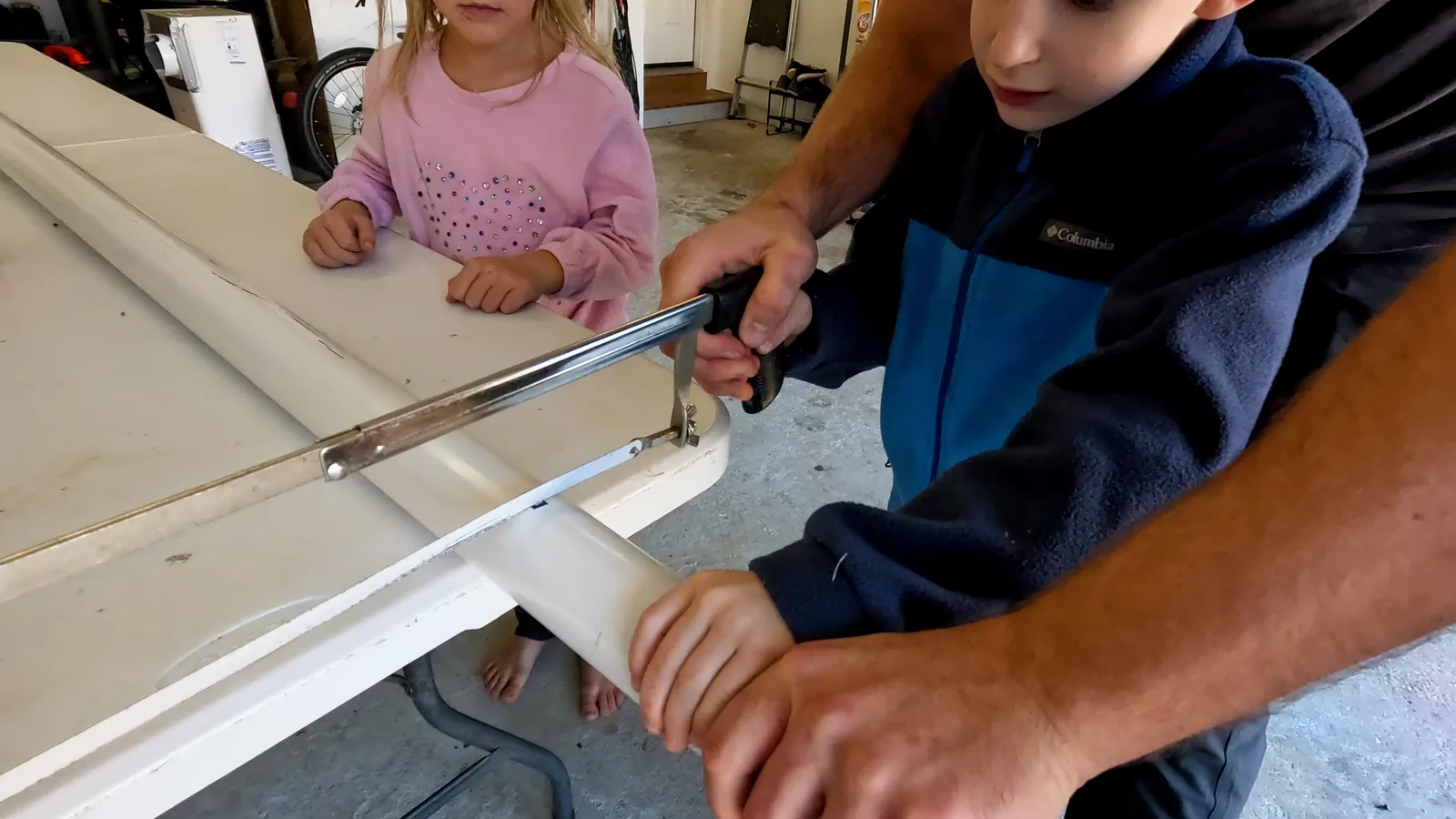 Kids cut PVC pipe with a hack saw