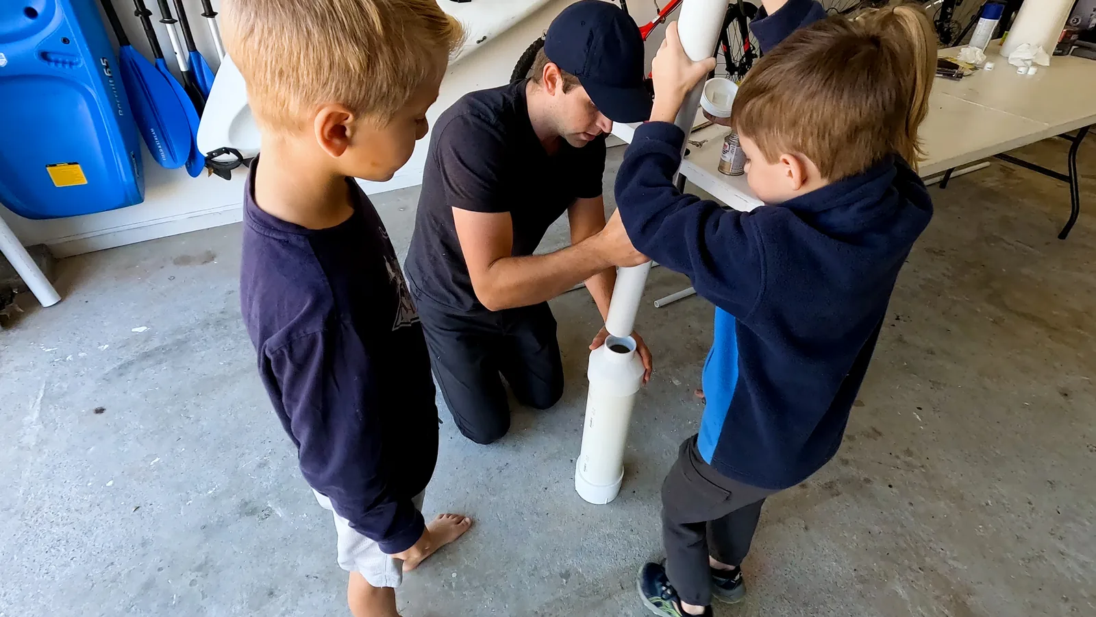 Kids and man glue PVC potato cannon together