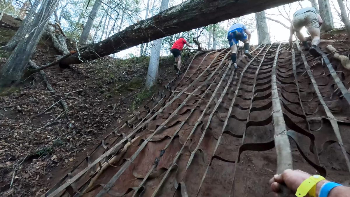 Adults climbing webbing obstacle
