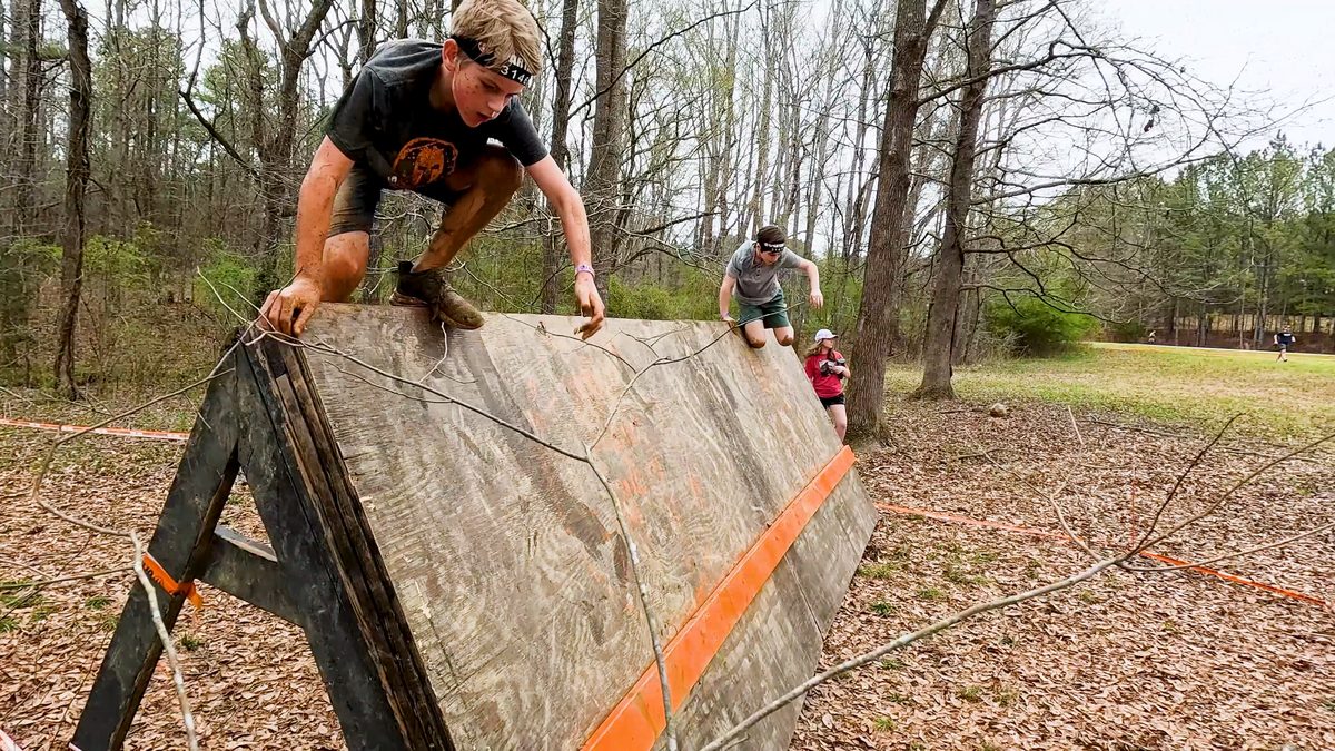 Kid jumps over wall in obstacle course race
