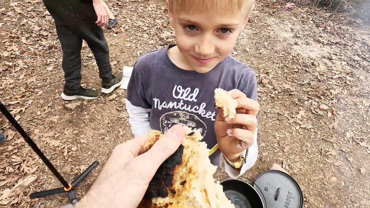 A boy trying the campfire bread.