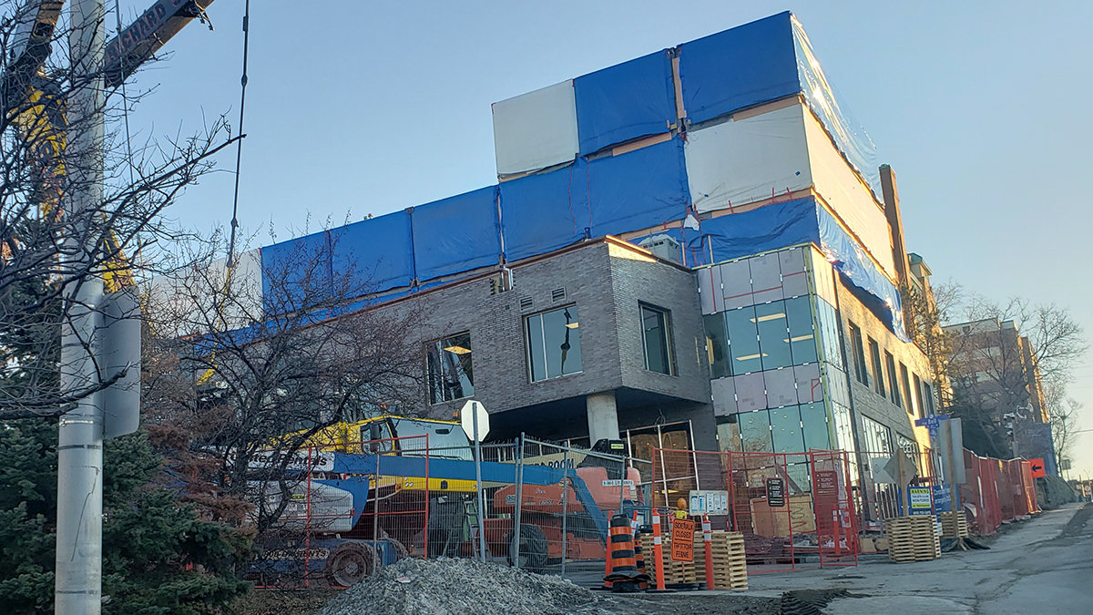 Modular building under construction with crane installation and site safety measures in place.