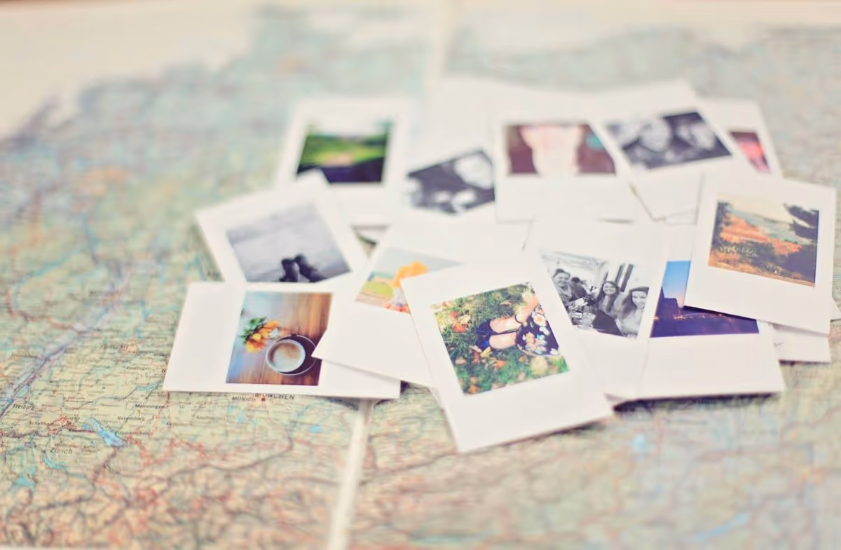 Scattered vintage-style instant photos with various images placed on a detailed map.