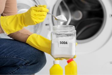 Woman adding a spoon of baking soda to the laundry machine