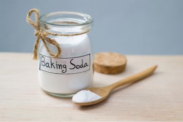 A jar with baking soda and a wooden spoon