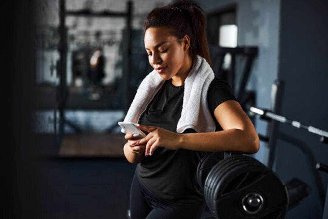 woman using a phone in a gym - Workout Quotes