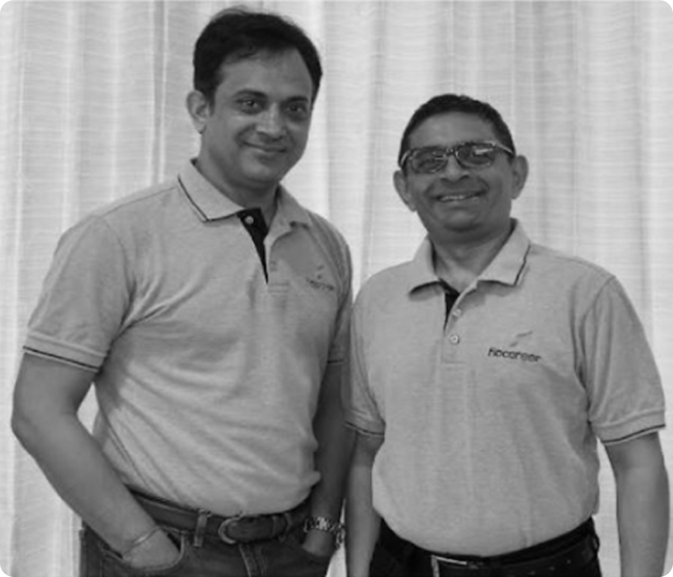 Two men smiling, wearing short-sleeve polo shirts and standing in front of a curtain backdrop.