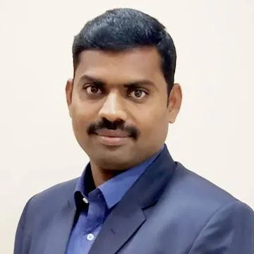 Portrait of a man with dark hair and mustache wearing a blue shirt and dark blazer.
