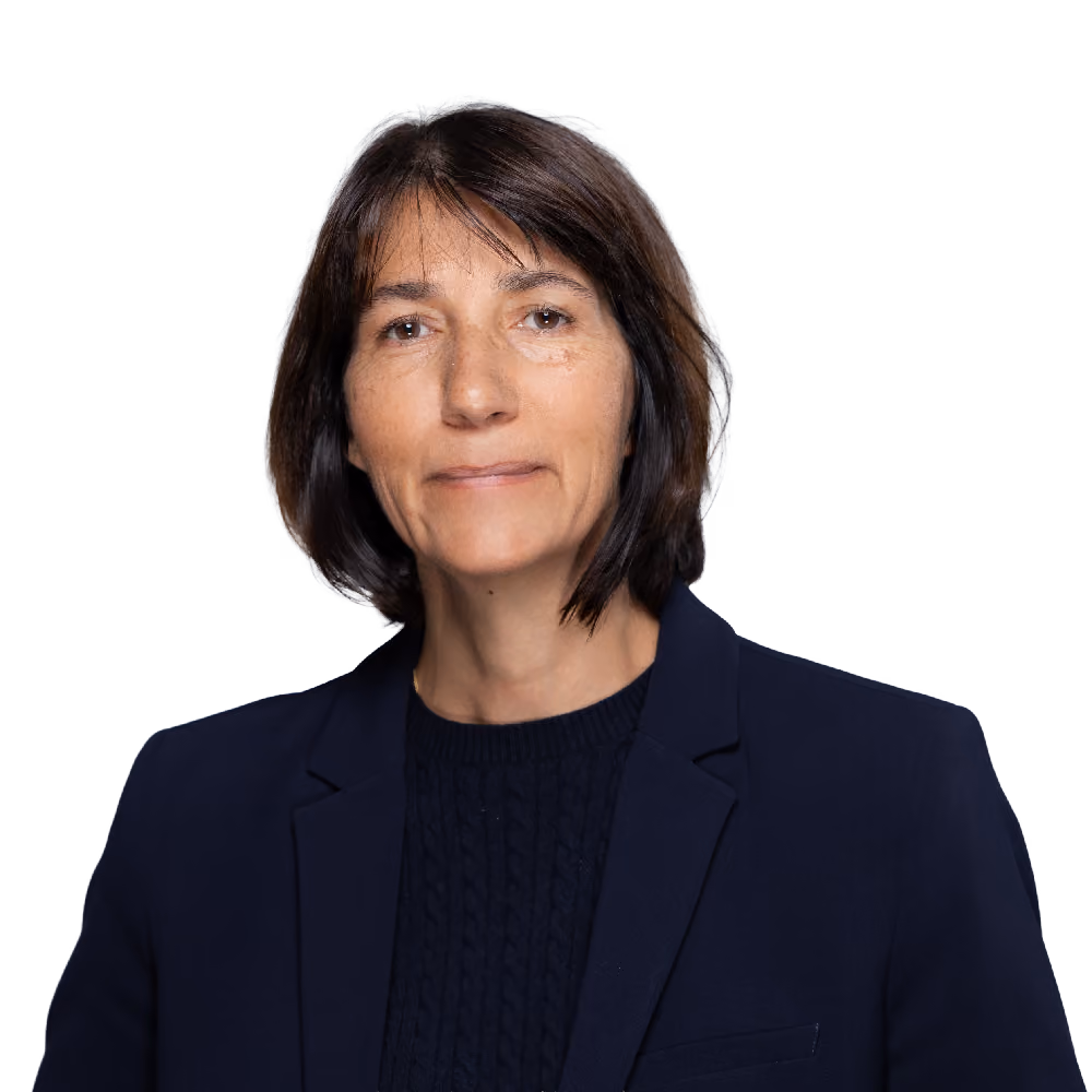 Woman with short brown hair wearing a dark blue blazer and sweater against a gray background.