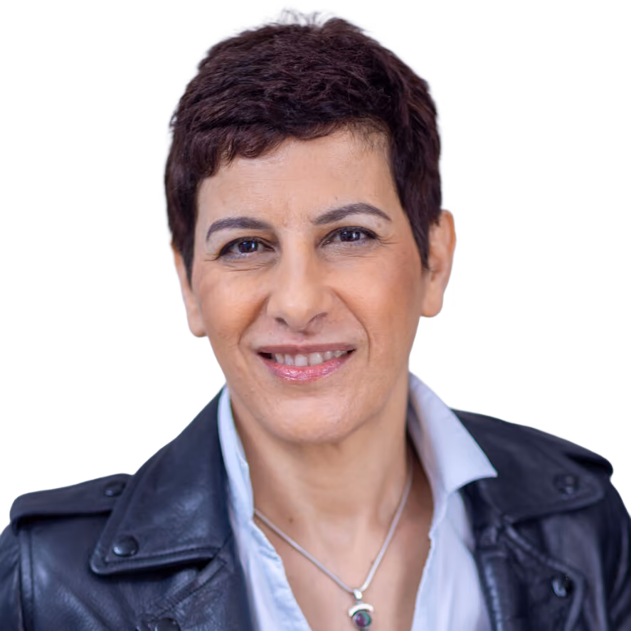 Smiling person with short dark hair in a black leather jacket and white shirt against a gray background.