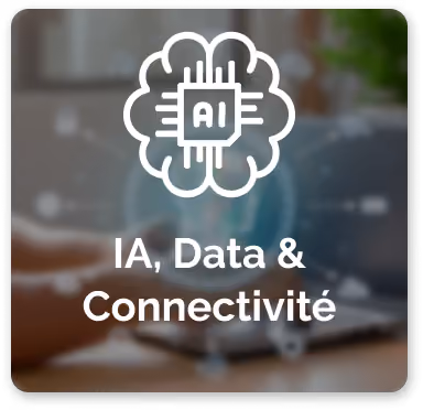 Illustration d'un cerveau stylisé avec une puce de circuit intégré au centre marquée 'AI', représentant l'intelligence artificielle, avec le texte 'IA, Data & Connectivité' en dessous, sur un fond flou d'une personne utilisant un ordinateur portable.