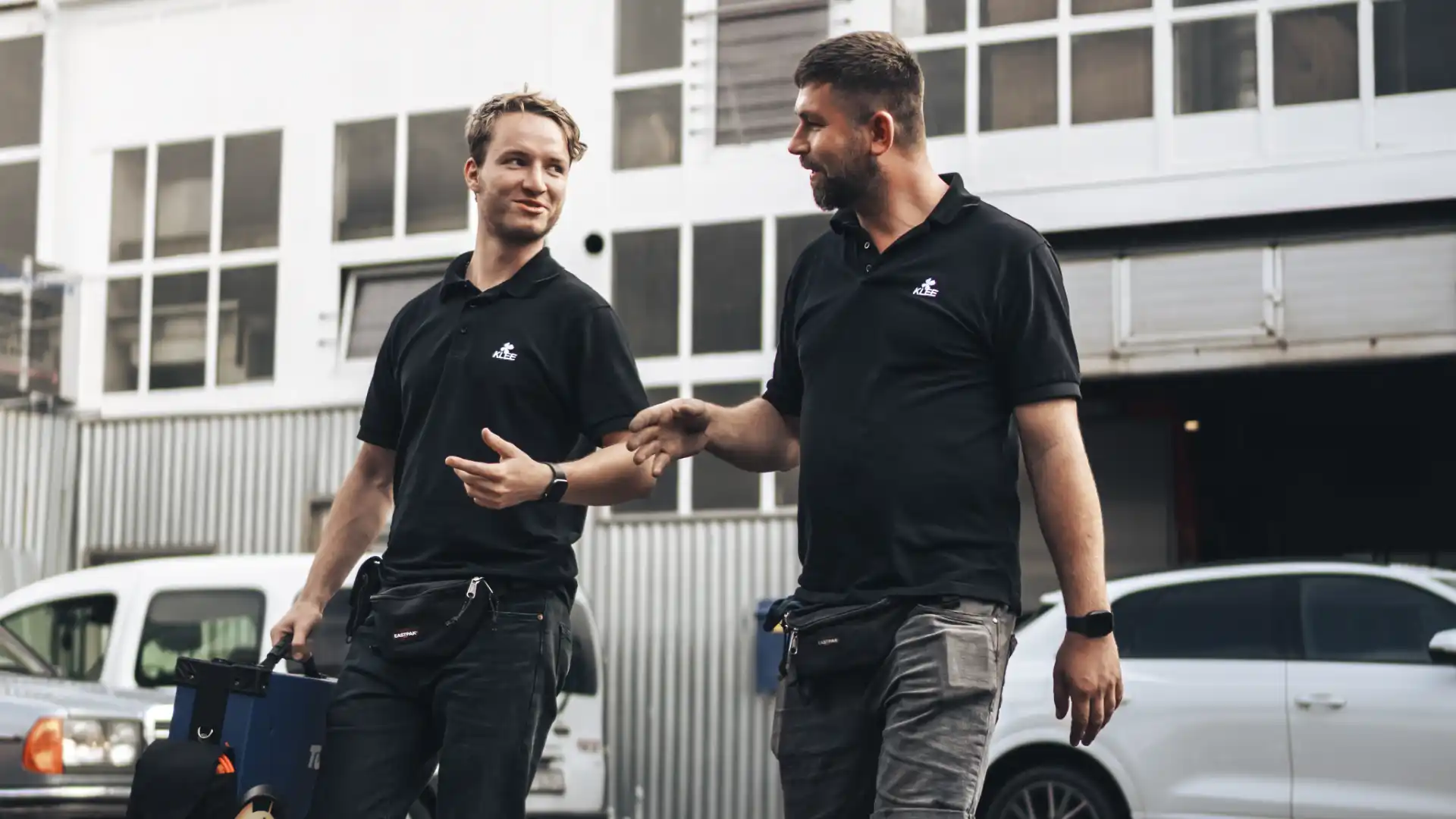 Sven und Martin von KLEE-sicher laufen zur TÜV Prüfstelle, um eine Hauptuntersuchung und Abgasuntersuchung (HU/AU) durchzuführen – Ihr Partner für TÜV Prüfungen und flexible TÜV Termine.