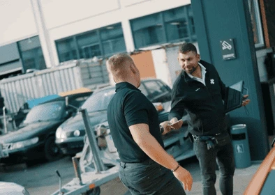 Sven übergibt dem Kunden die Prüfunterlagen nach erfolgreicher Hauptuntersuchung (HU/AU) bei KLEE-sicher – TÜV Prüfung transparent und persönlich erklärt.