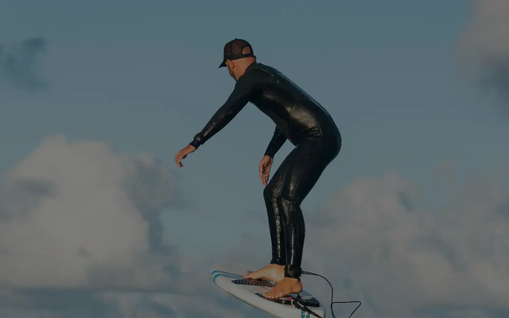 surfer in a wet suit riding a surfboard in the ocean