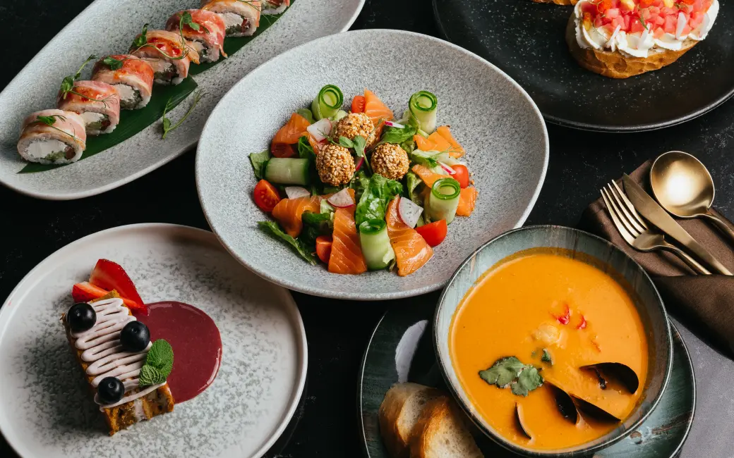 several plates of food are arranged on a table with silverware