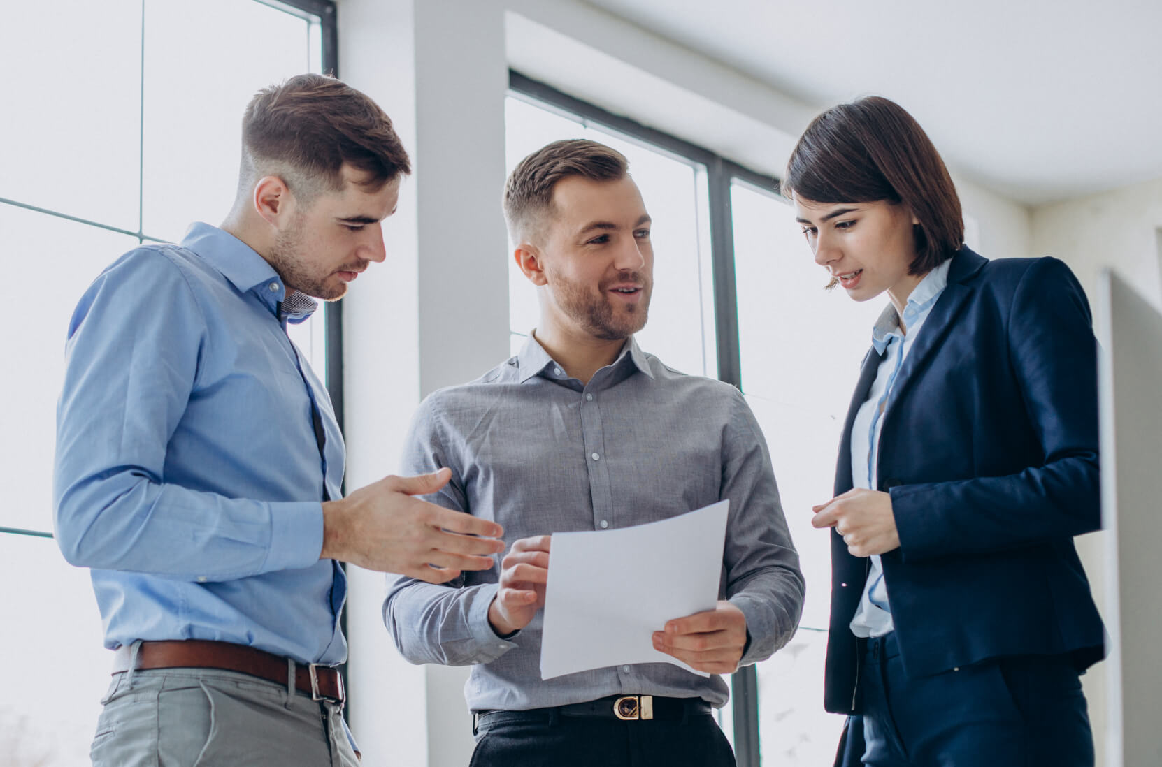 A group of people standing around each other in a room.