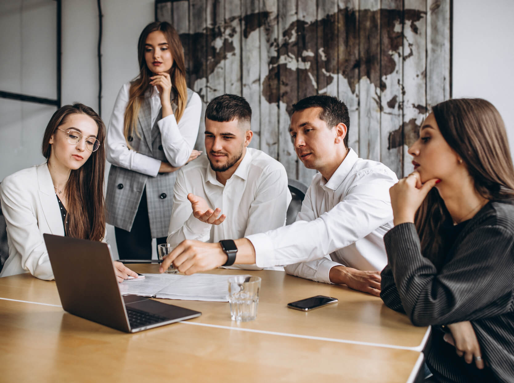 A group of people sitting around a wooden table.