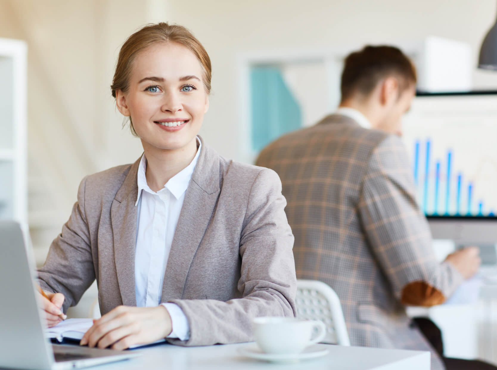 A woman sitting at a desk in front of a laptop computer.