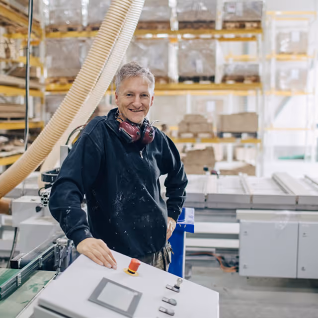 Okno moderního domu s pohledem na světlou pohovku a zelenou zahradu venku.