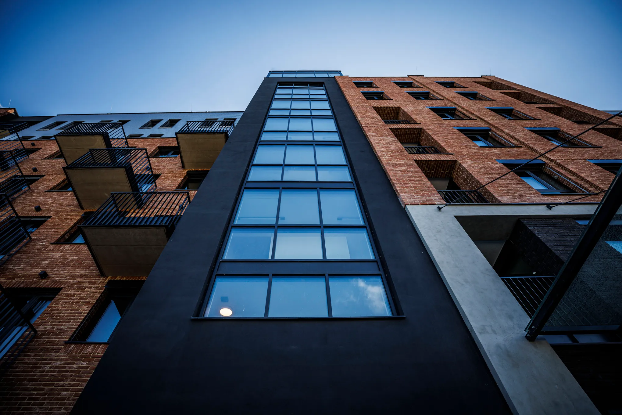 Vnitřní kancelářský prostor s obloukem pokrytým zelenou rostlinnou stěnou a nápisem SULKO, za kterým je posezení s moderními křesly a televizí.