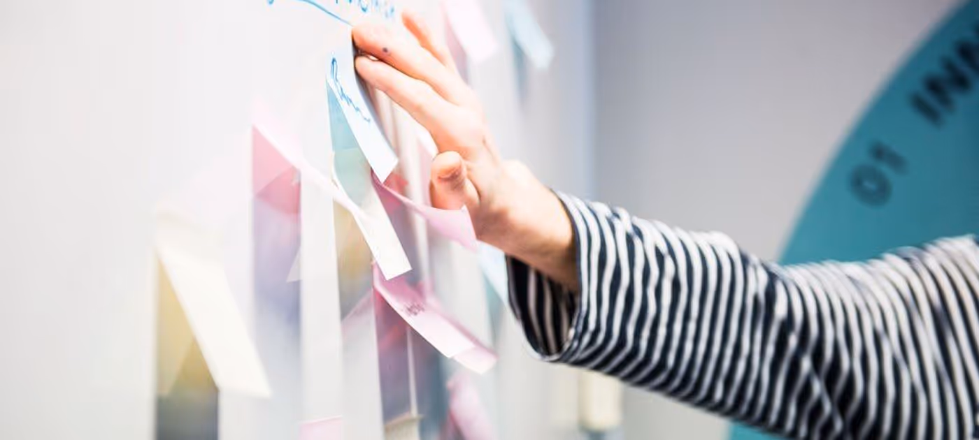 En person i stripete genser fester lapper på en glassvegg.