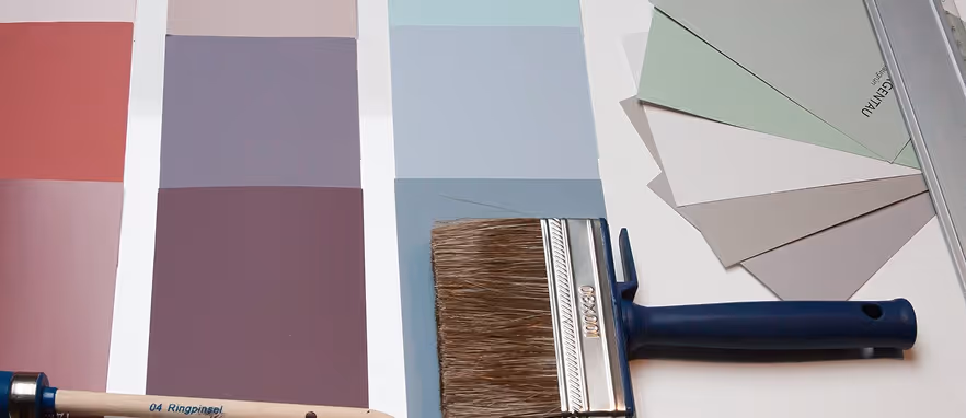 Maltpensel og fargeprøver med nyanser av rosa, lilla, blått og grått.